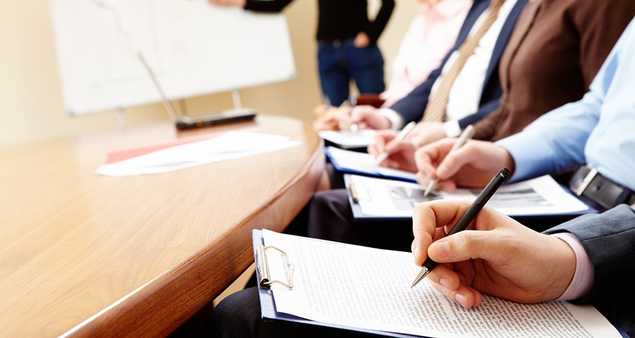 Close-up of businesspeople hands holding pens and papers near table at business seminar